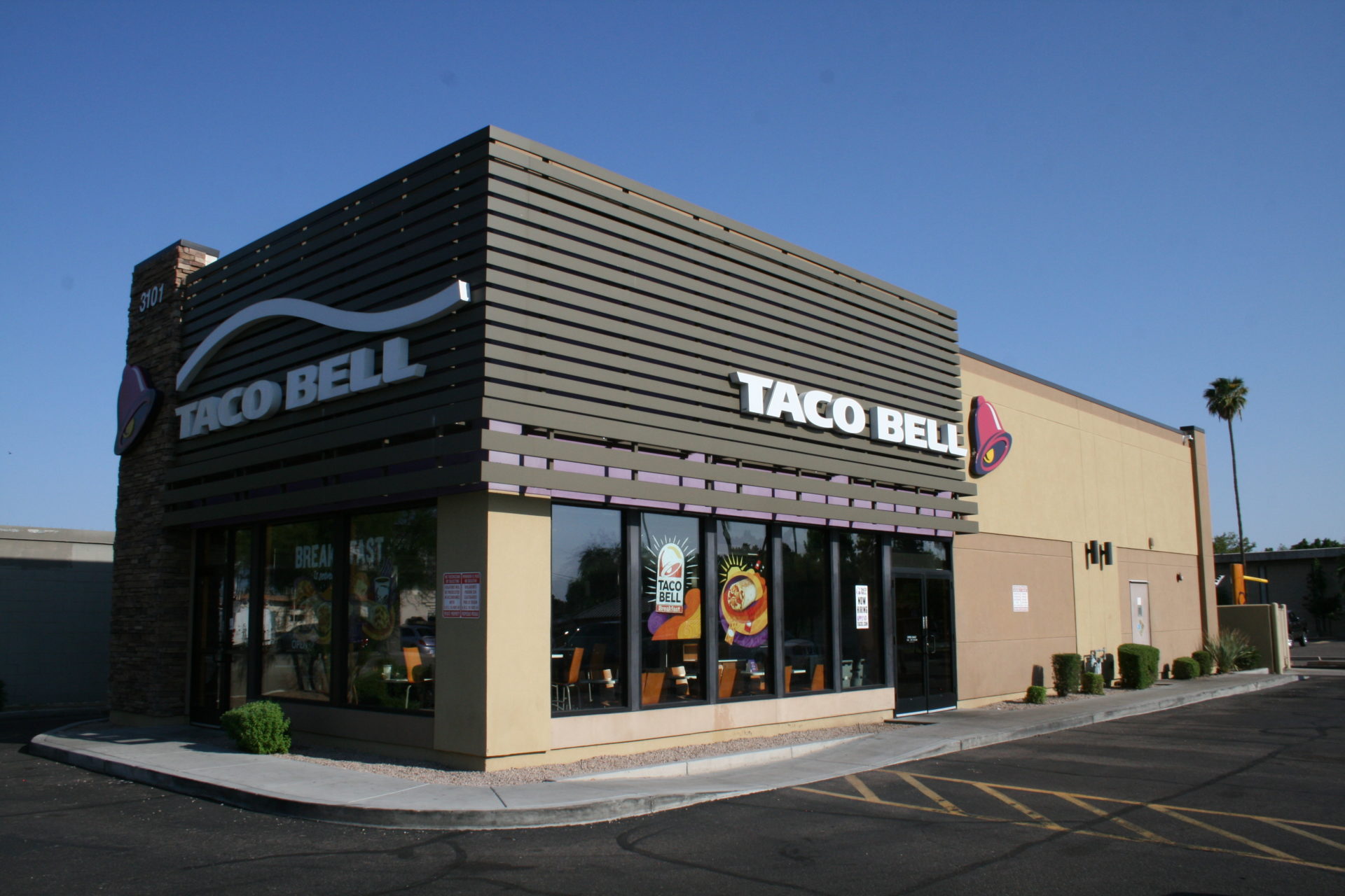 A taco bell restaurant with a parking lot in front.
