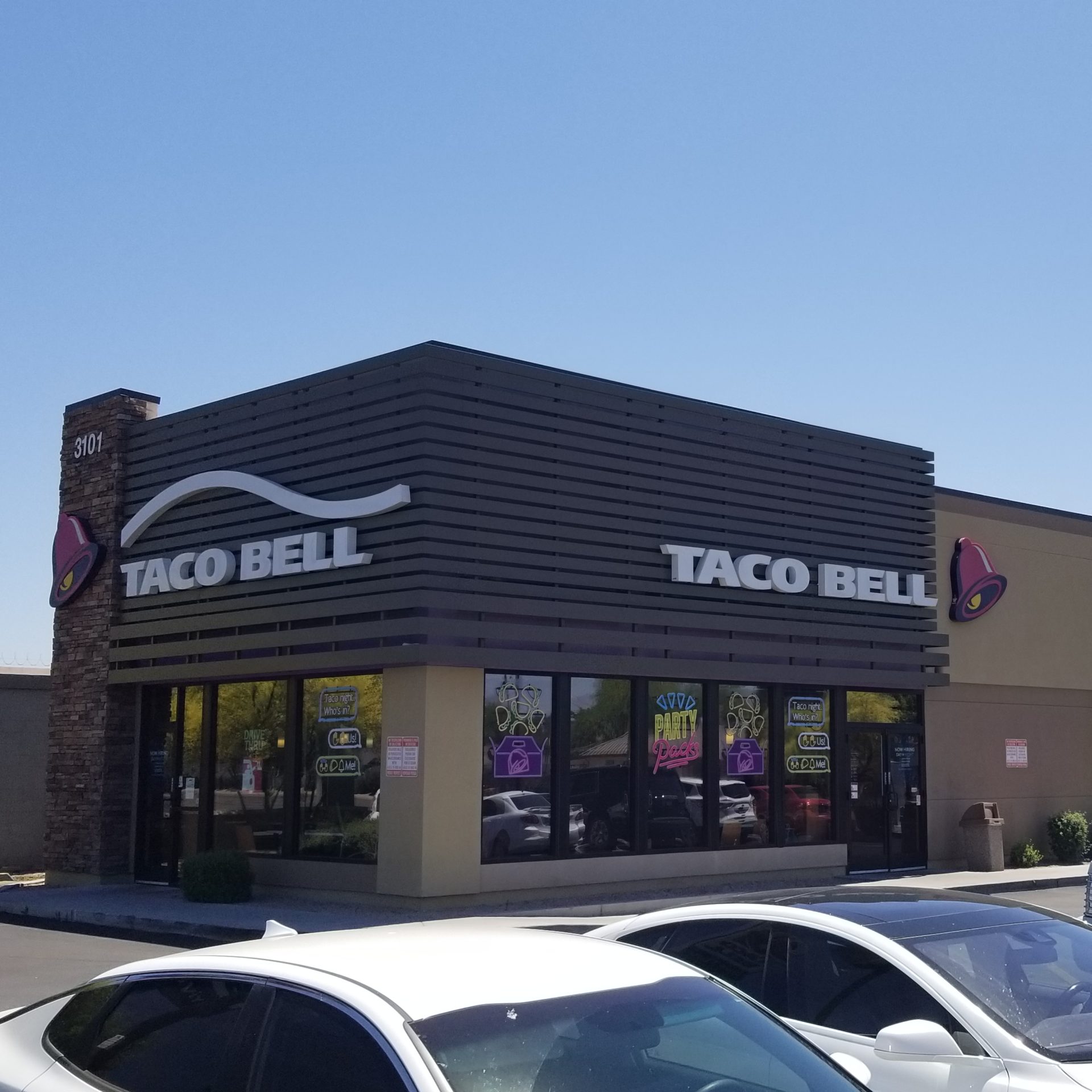 A taco bell with cars parked in front of it.
