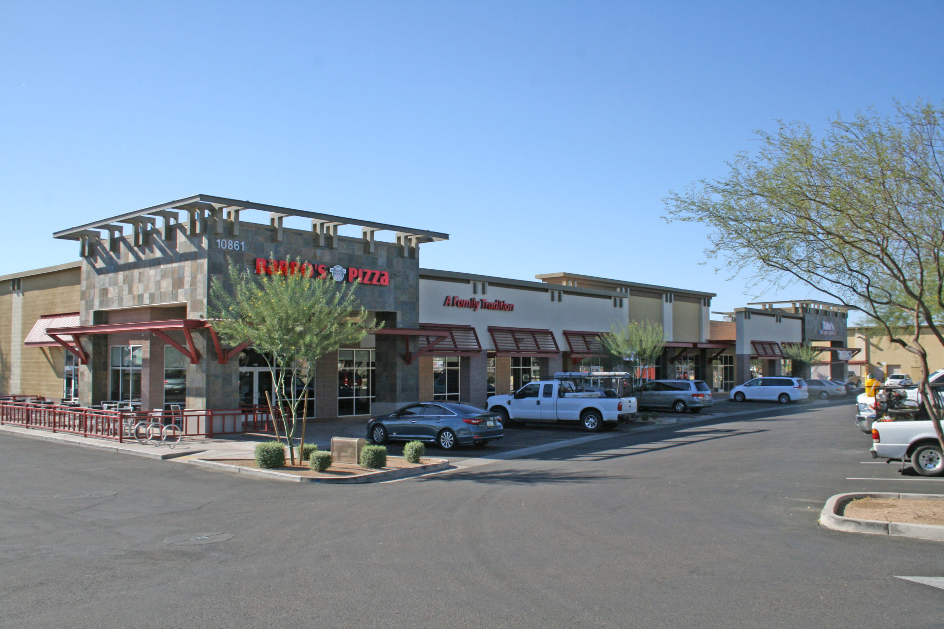 A street view of several businesses in the middle of a parking lot.
